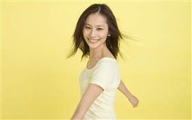 幸せなアジアの女の子、黄色の背景